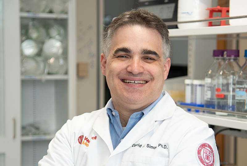 a man in a white coat posing for a picture in a lab