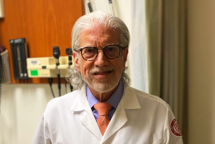 a man in a white coat posing for a picture in a lab
