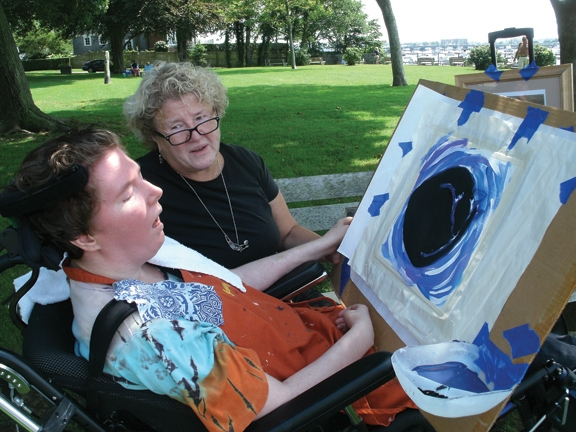 Nancy and Maggie Worthen sitting in a park. Maggie has a blue circle painting in front of her