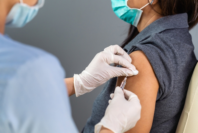photo of masked person administering vaccine to another masked person