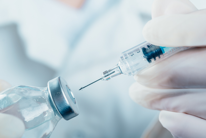 photo of a gloved hand inserting a syringe into a vial