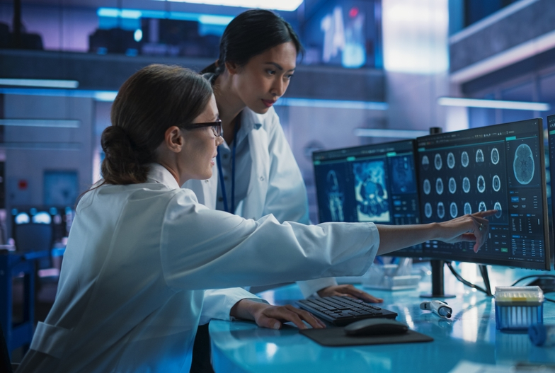 two women in white coats look at MRI scans