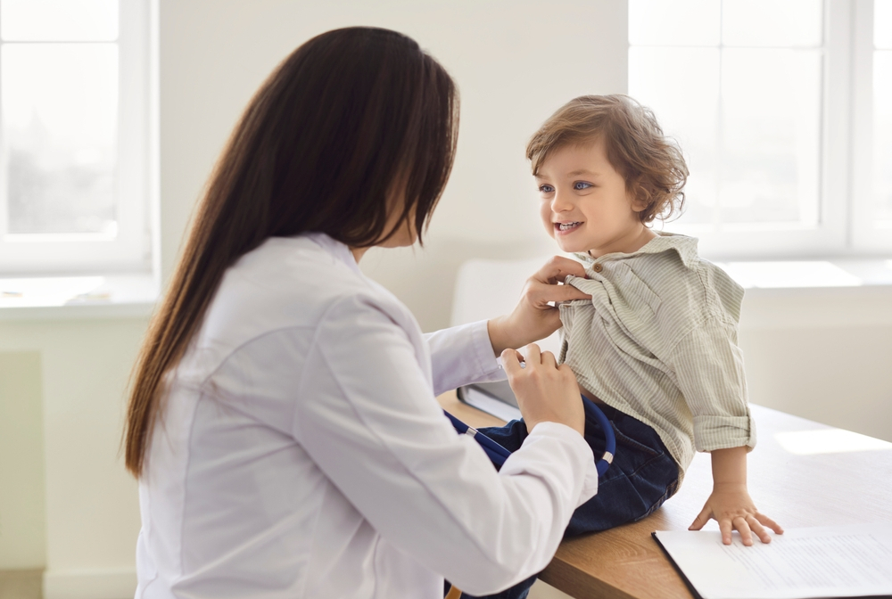 A pediatrician examining a child with a stethoscope.