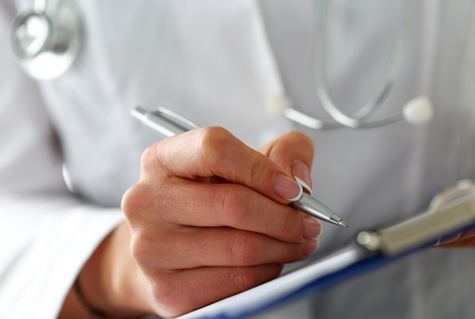 closeup of doctor's hand writing in chart