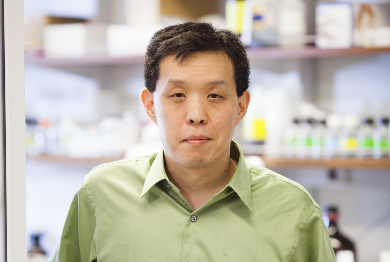 a man in great shirt in a lab posing for a portrait.