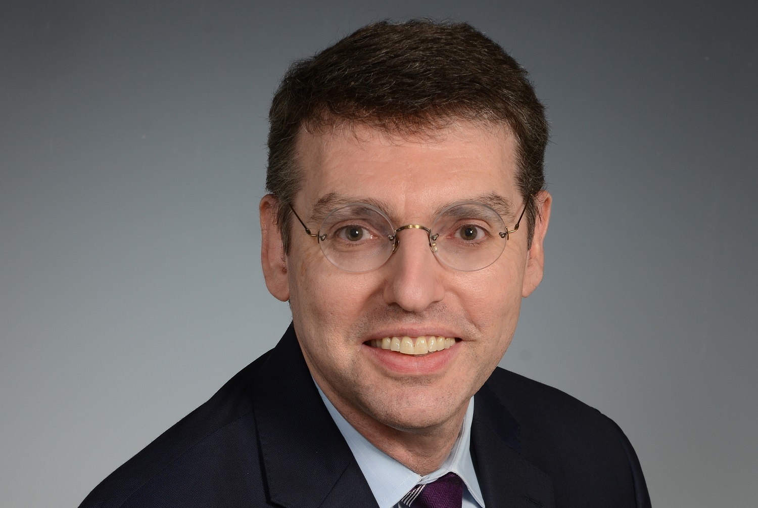 a man in a suit and glasses posing for a photo