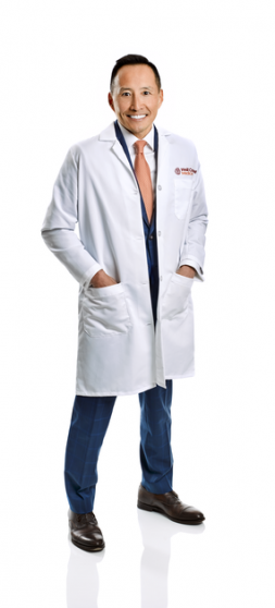a man in a white coat posing and smiling