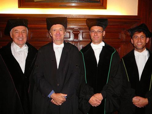 four men in academic caps and gowns