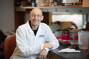 man in white coat sitting at desk