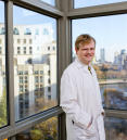 a man in a white coat posing for a picture in a lab