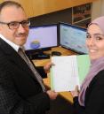 Laith Abu-Raddad and Susanne Awad holding a paper with charts and graphs