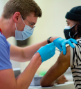 a person getting a vaccine shot from a md phd student
