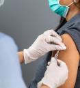 photo of masked person administering vaccine to another masked person